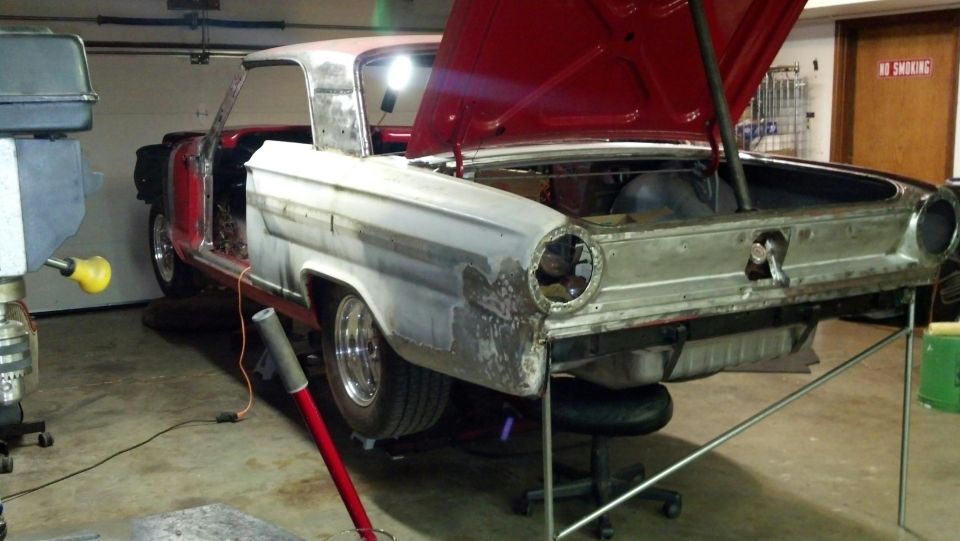 1964 Ford Fairlane in garage, hood and doors open, undergoing restoration