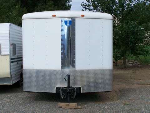 1988 Suzuki Samurai - A white enclosed trailer is parked next to another trailer, with trees in the background.