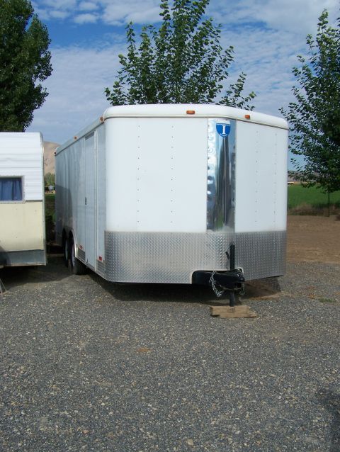 1988 Suzuki Samurai - A white enclosed trailer is parked on a gravel lot next to another trailer under a partly cloudy sky.