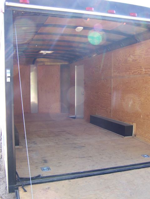 1988 Suzuki Samurai - The interior of a cargo trailer is shown, wooden walls and floor, with tie-down anchors visible.