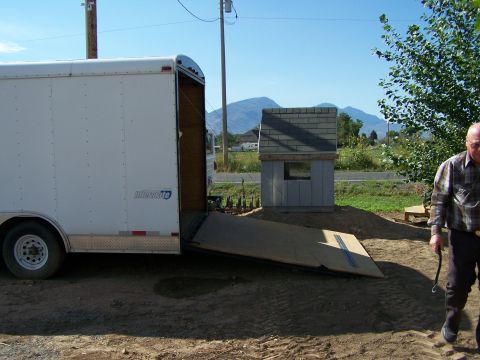 1988 Suzuki Samurai - A white cargo trailer is parked outdoors with its ramp extended, next to a man and a small building.