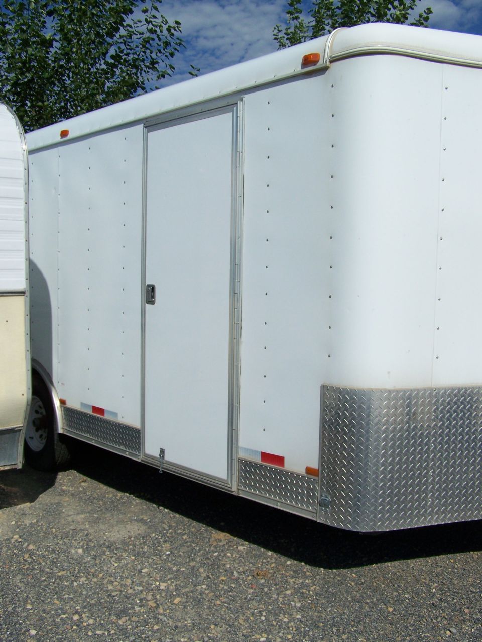 White enclosed trailer with a sliding door and diamond plate trim