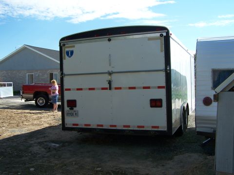 1988 Suzuki Samurai - A red pickup truck is parked next to two trailers under a blue sky.