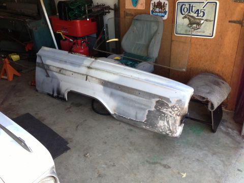 1964 Ford Fairlane - A car fender sits in a garage, showing signs of bodywork and preparation for a new paint job.