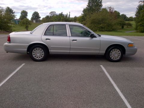2001 Ford Crown Victoria - A silver sedan is parked in a lot with trees in the background.