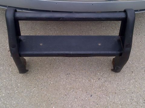 2001 Ford Crown Victoria - A black bull bar is shown resting on a concrete surface, with the front of a silver vehicle visible in the background.