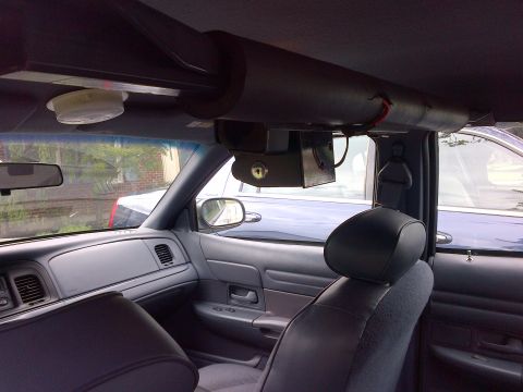 2001 Ford Crown Victoria - The interior of a car shows a custom overhead console and equipment, with another vehicle visible outside.