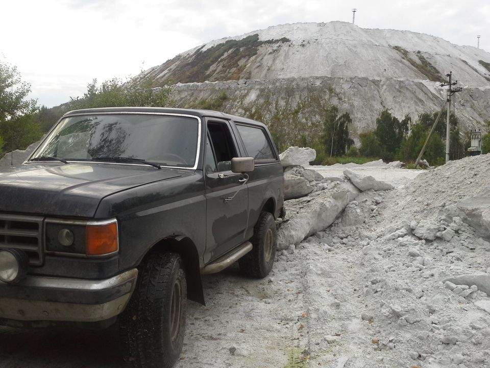 1987 Ford Bronco parked on dirt road with white mountain in background