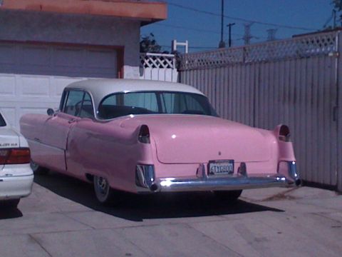 1968 Ford Mustang - A classic pink and white Cadillac sedan is seen from the rear, parked in a driveway.