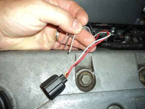 2004 Mercury Grand Marquis - Close-up of a hand holding an electrical connector and wires, positioned near a metallic engine component.