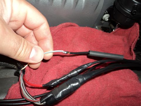 2004 Mercury Grand Marquis - Close-up of a hand performing a wiring splice with electrical tape and heat shrink tubing.