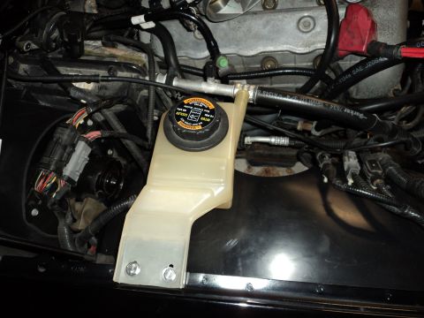2004 Mercury Grand Marquis - Close-up view of engine bay components, including a coolant reservoir and various hoses.