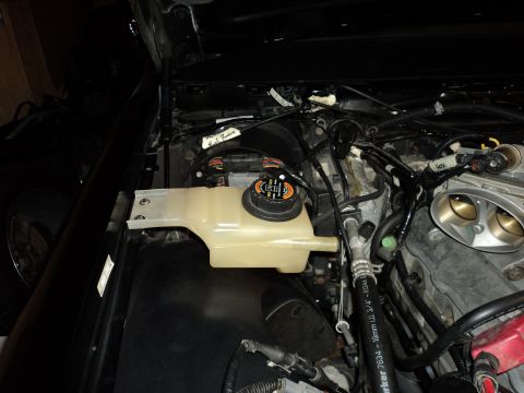 2004 Mercury Grand Marquis - Close-up view of an engine bay, focusing on the coolant reservoir and various hoses and wiring.