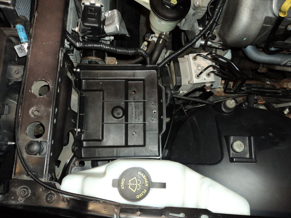 Engine bay with battery tray, washer fluid reservoir, and ABS module visible