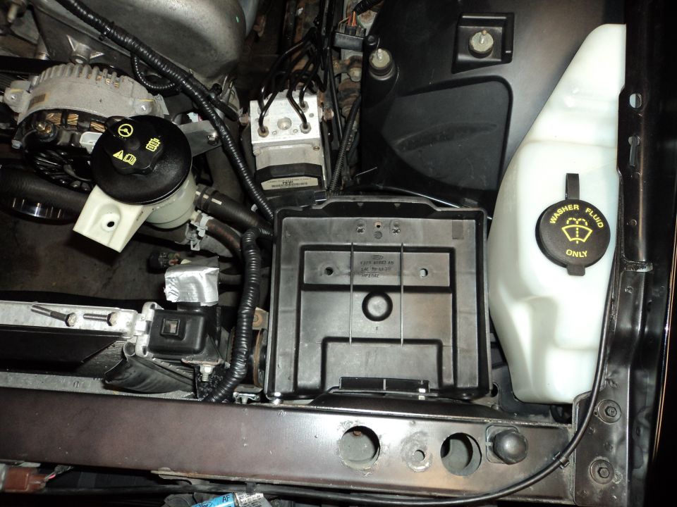 engine bay with washer fluid reservoir, power steering reservoir, and ABS module visible