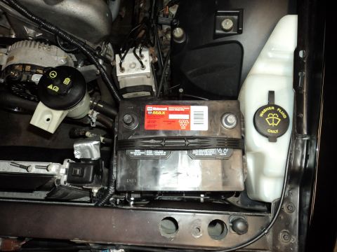 2004 Mercury Grand Marquis - Close-up view of a car's engine bay, focusing on the battery and washer fluid reservoir.