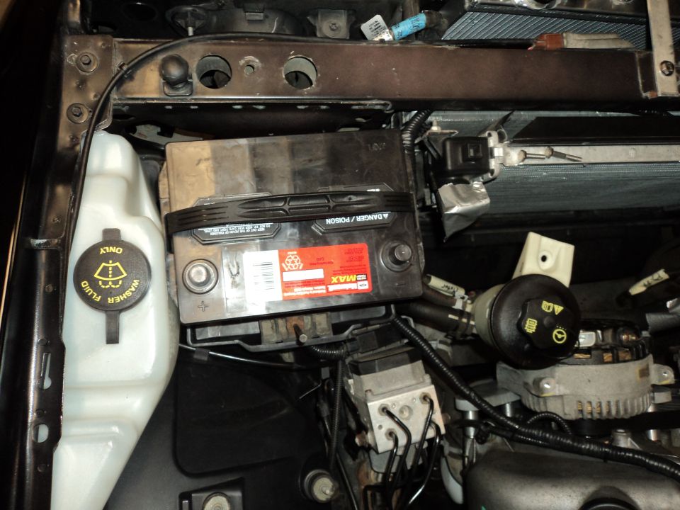 Engine bay showing battery, washer fluid reservoir, and alternator