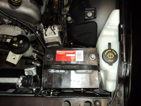 2004 Mercury Grand Marquis - Close-up of a car battery and washer fluid reservoir, part of engine bay components.