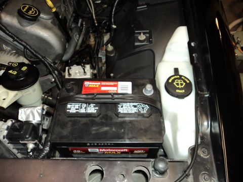2004 Mercury Grand Marquis - Close-up view of a car battery and washer fluid reservoir in the engine bay.