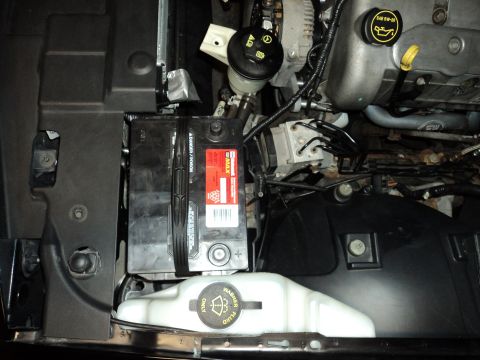2004 Mercury Grand Marquis - Engine bay view showing a car battery, master cylinder, and other engine components.