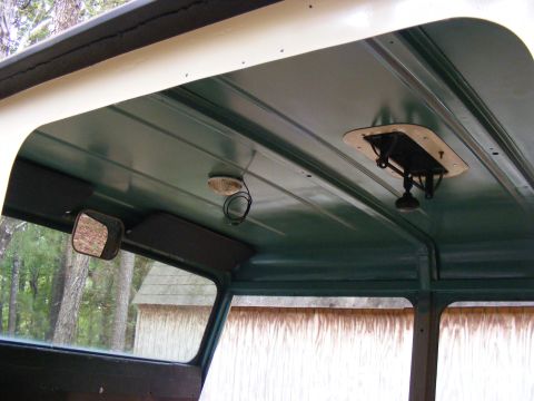 Interior ceiling of a vehicle with a vent, dome light, and side mirror visible