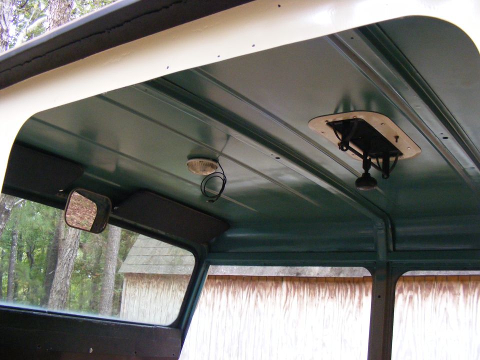 Interior ceiling of a vehicle with a vent, dome light, and side mirror visible