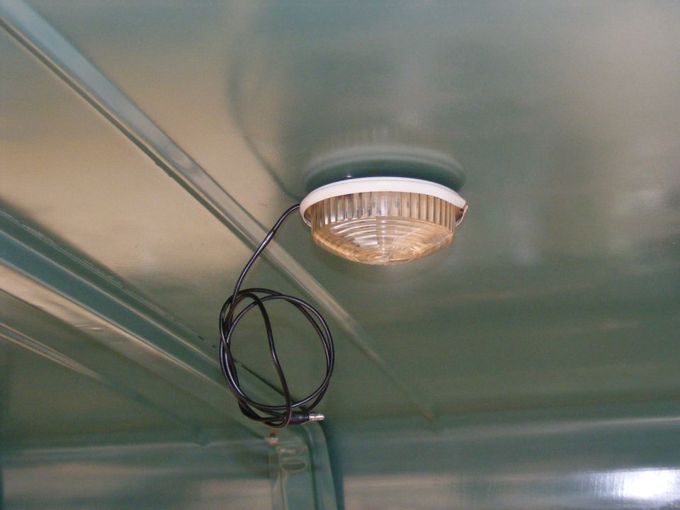 Interior dome light with black wire coiled beside it, mounted on a green ceiling