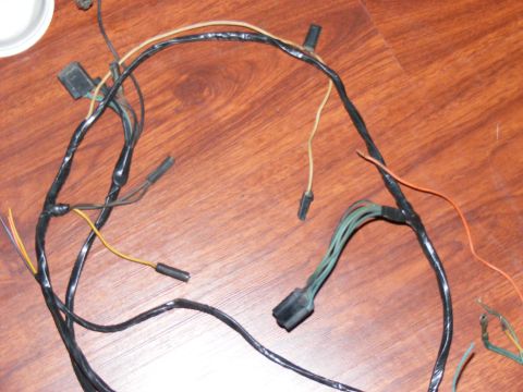 Wiring harness with black tape and multiple connectors on a wooden surface