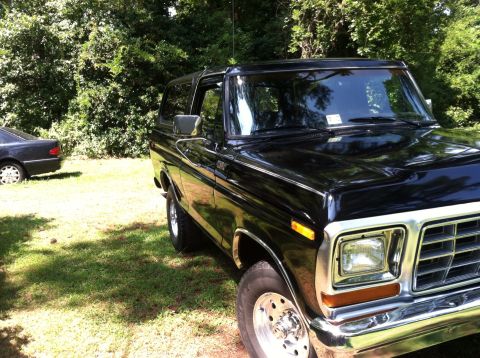 1978 Ford Bronco - A black 1978 Ford Bronco is parked outside on a sunny day with trees and grass surrounding it.