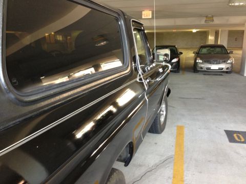 1978 Ford Bronco - Side view of a black 1978 Ford Bronco in a parking garage with other vehicles.