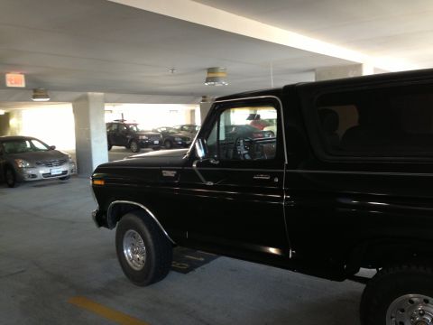 1978 Ford Bronco - A black 1978 Ford Bronco is parked in a dimly lit parking garage, with other vehicles in the background.