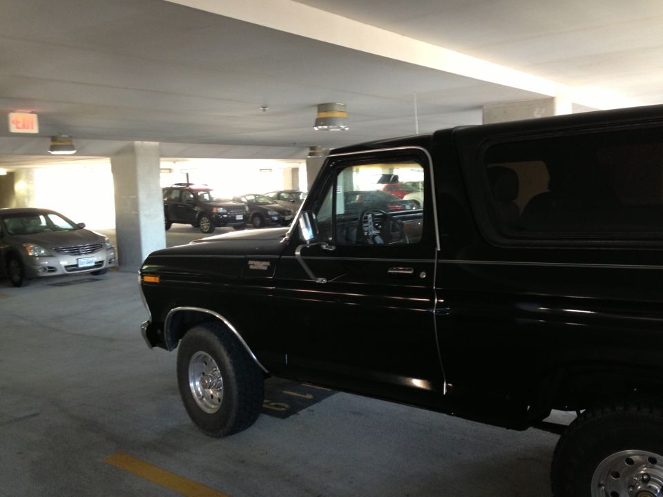 Black 1978 Ford Bronco parked in a garage, side view. Other cars are visible in the background