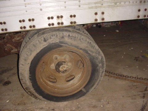 1992 Ford Bronco - Dual rear wheels of a trailer are shown with flat tires in a dimly lit garage.