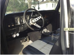 1978 Ford Bronco - The interior of a black vehicle is shown, two-tone seats and an aftermarket steering wheel.