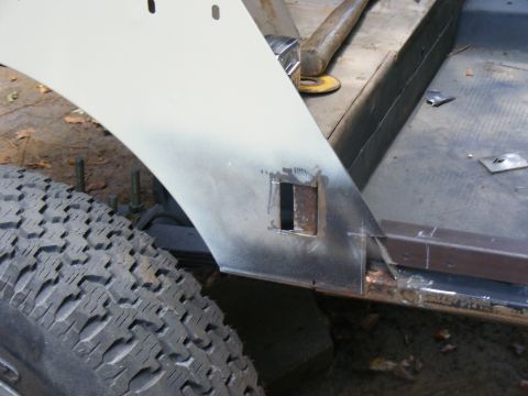 Close-up of a vehicle's rear fender area being worked on, showing metal fabrication and a tire