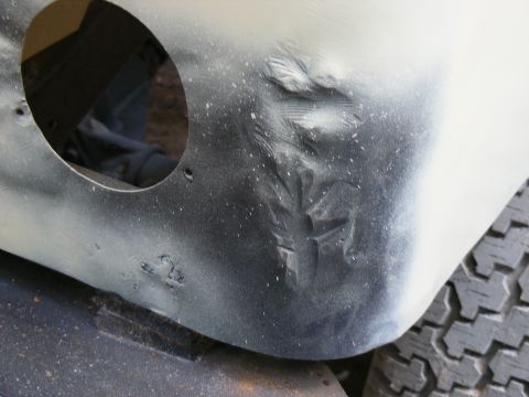 Fender with a large dent and spray paint splatter. Tire tread visible