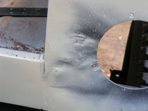 White vehicle panel with dents and circular cutout, ruler visible