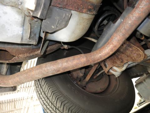 1991 Ford LTD Crown Victoria - The underside of a vehicle reveals significant rust on the exhaust system and suspension components.