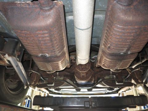 1991 Ford LTD Crown Victoria - The underside of a vehicle is shown, revealing rusted exhaust components and a drive shaft.
