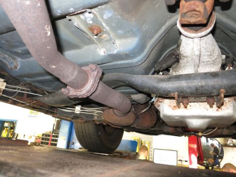 1991 Ford LTD Crown Victoria - Underside view of a vehicle's exhaust system and drive shaft, with a tire visible.