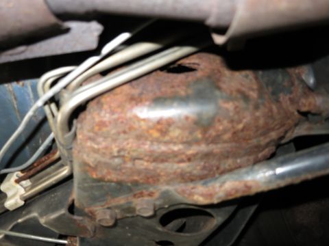 1991 Ford LTD Crown Victoria - Undercarriage view of a heavily rusted component with brake and fuel lines, indicating significant corrosion.