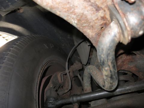 1991 Ford LTD Crown Victoria - Close-up of heavily rusted suspension parts and a tire, showing significant wear.