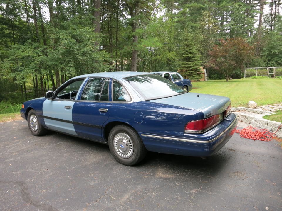 Blue and light blue Ford Crown Victoria parked on asphalt, rear-right view