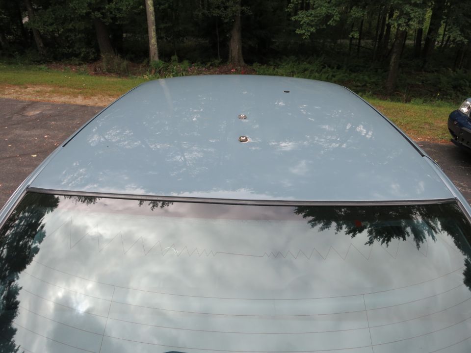 Top view of a light blue car roof showing three studs and reflection of trees in the rear window