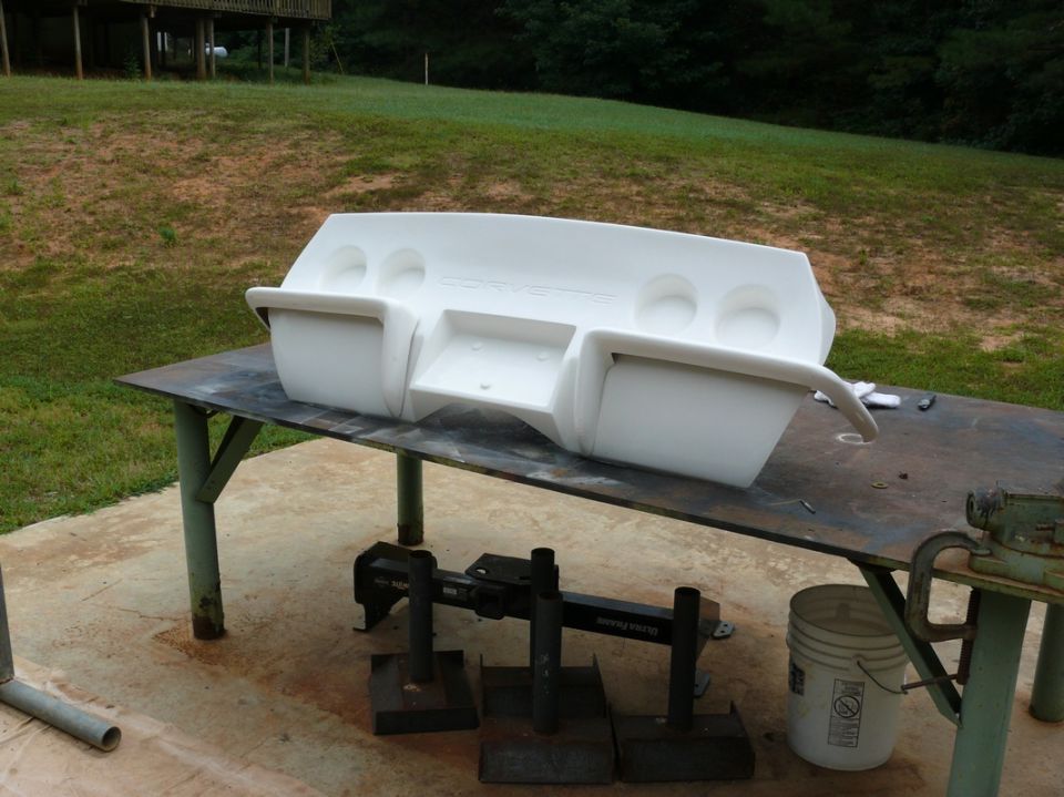White dashboard section with 'CORVETTE' molded into it, sitting on a metal table outdoors