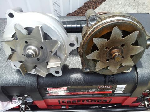 1990 Ford Bronco - Comparison of a new water pump with a corroded, used water pump, resting on a red and black toolbox.