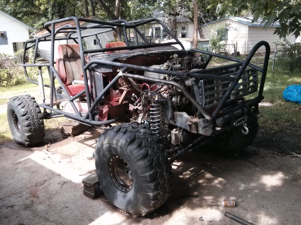 Custom buggy with roll cage, large tires, and exposed engine, sitting on blocks