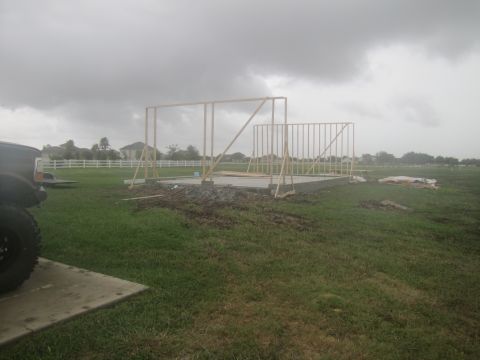 1995 Ford Bronco - A partial view of a black SUV is visible in the foreground, with a construction site in the background under a cloudy sky.