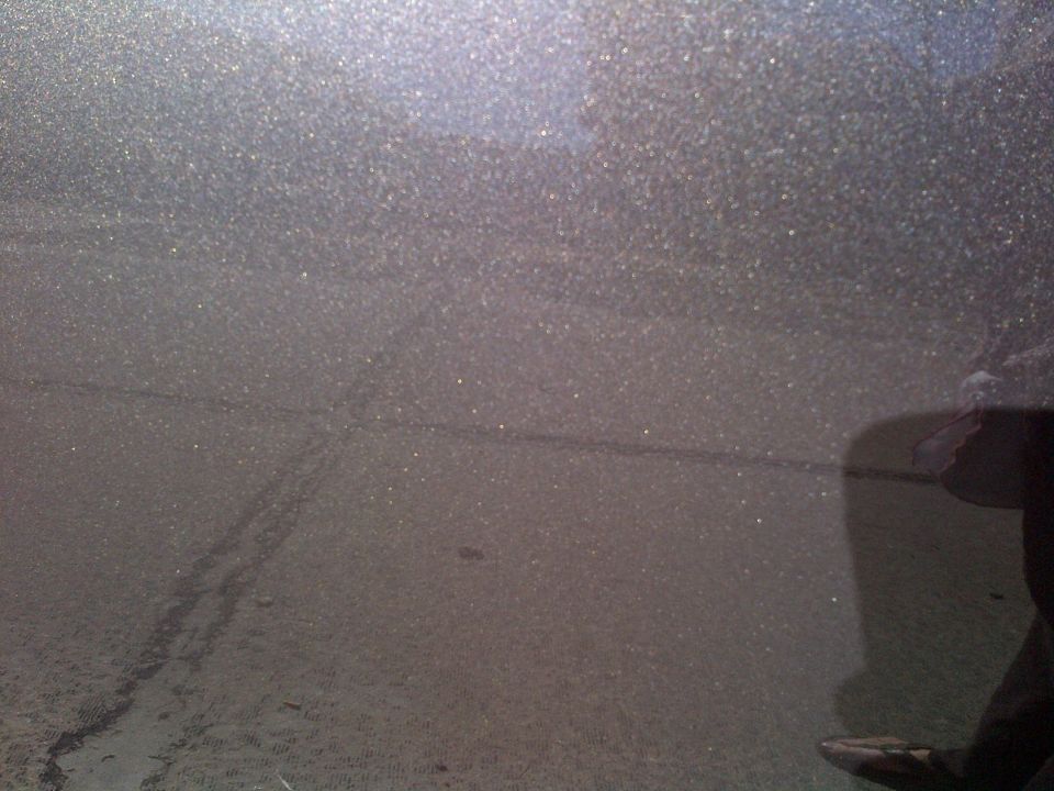 Dark gray metallic car door with faint scratches and a reflection of a person