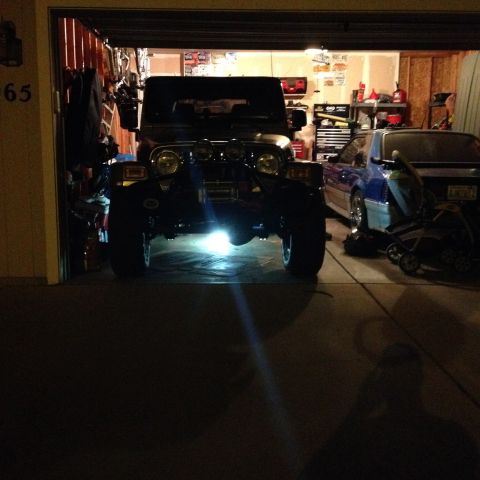 2005 Jeep Wrangler - A black Jeep Wrangler is parked inside a garage, with another vehicle and a stroller nearby.